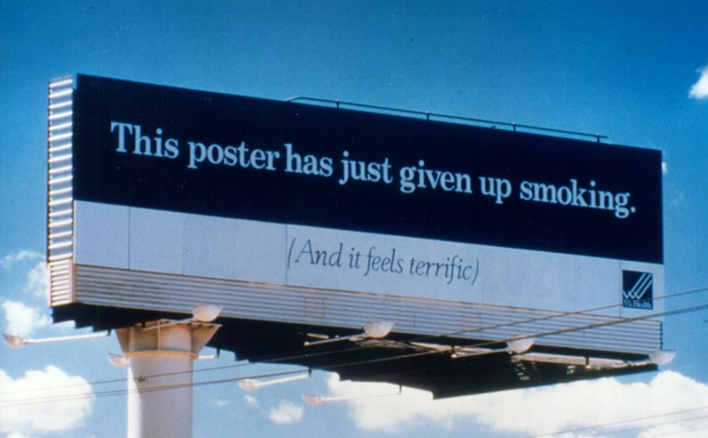 A photo of a billboard reading "This poster has just given up smoking. (And it feels terrific)".