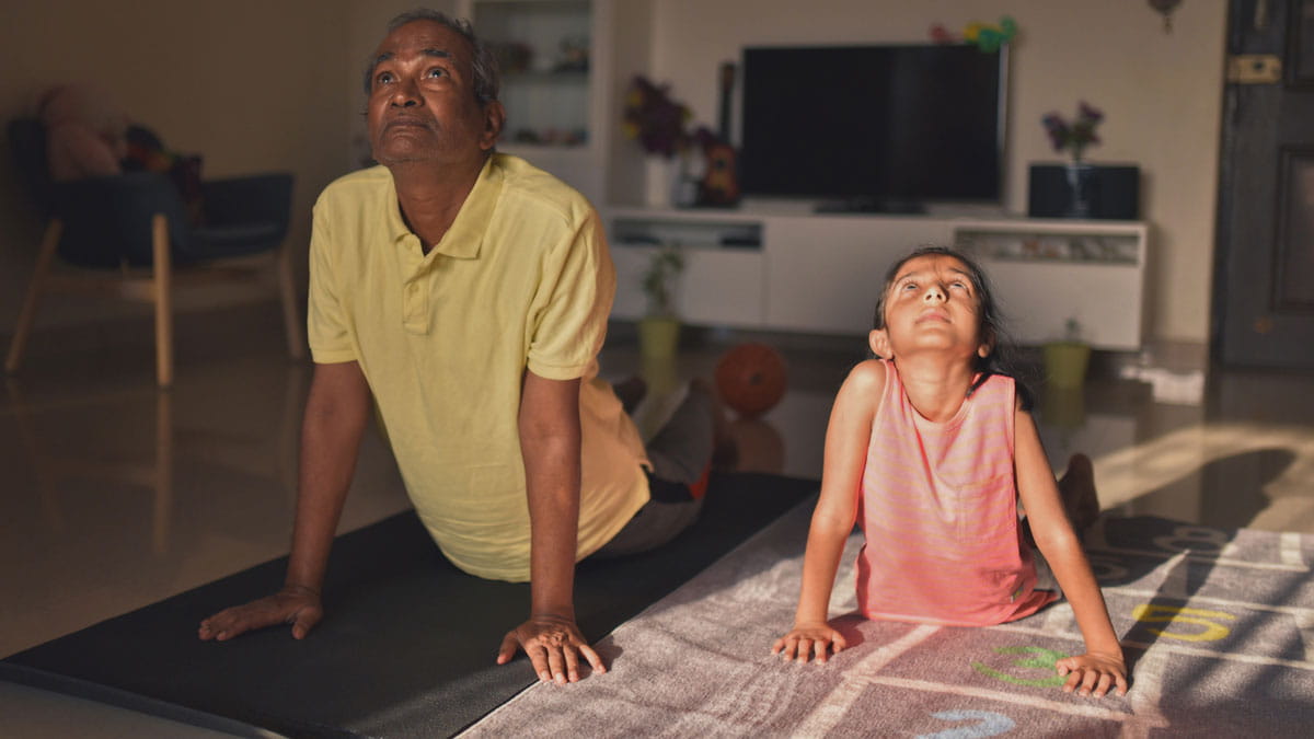 Grandfather and grand daughter doing yoga at home
