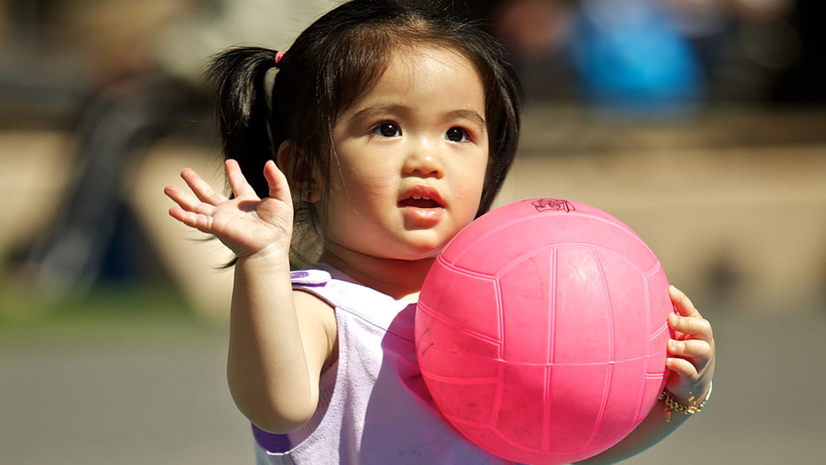 Small girl holding a ball and waving