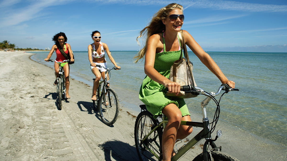 Young women riding bikes on the beach