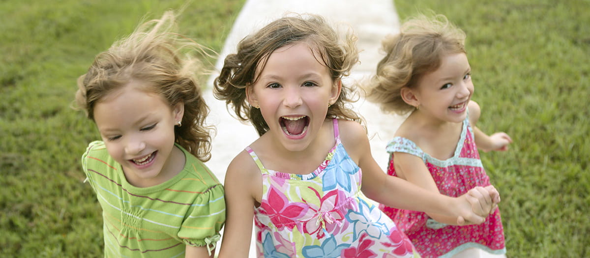 Three young girls laughing and running together