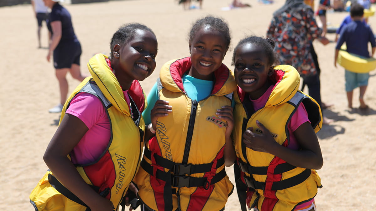 Three girls at the beach in lifejackets