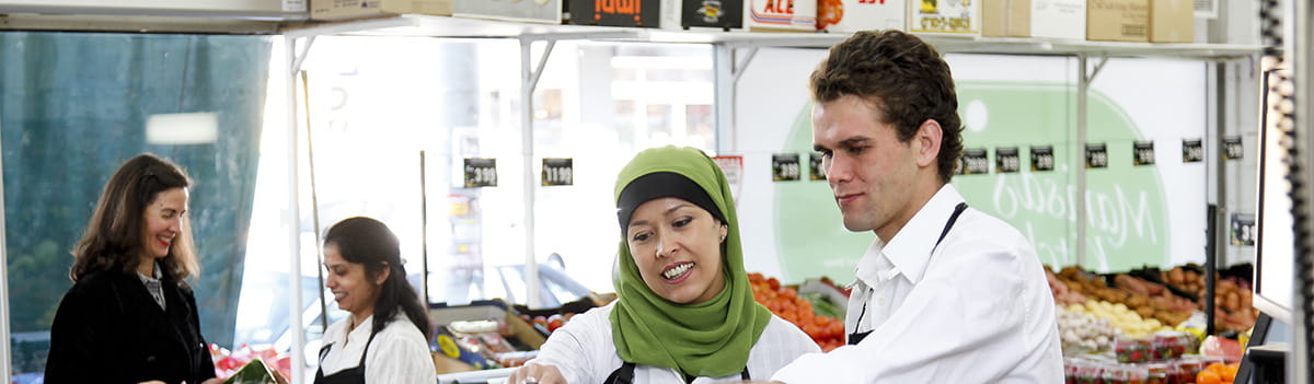 Culturally-diverse woman learning how to work at a supermarket