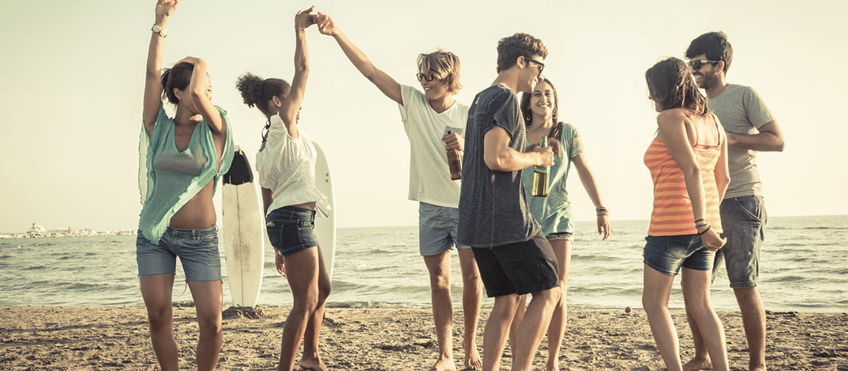 Young people drinking and dancing on the beach