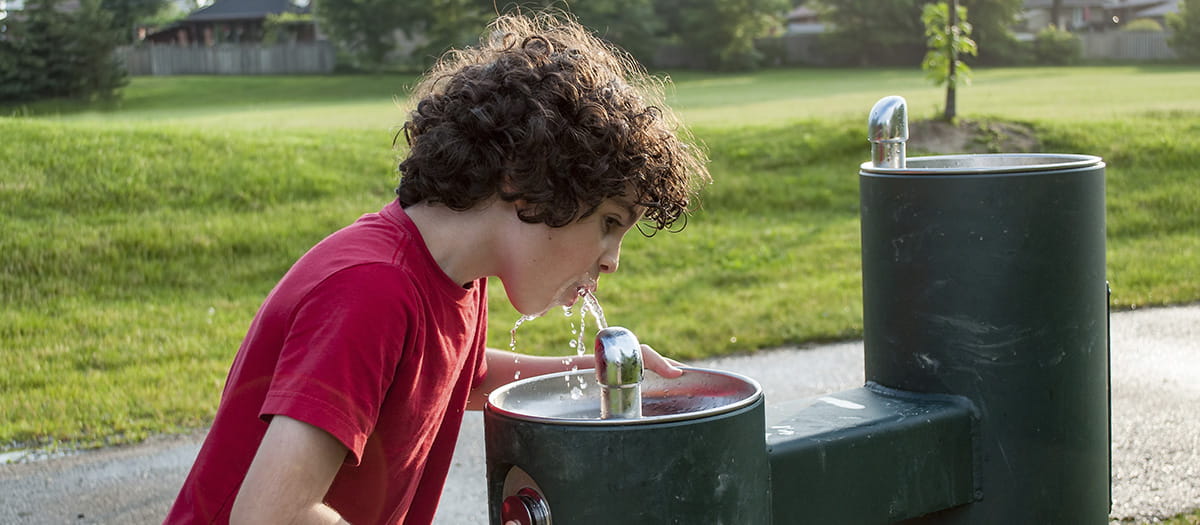 Boy drinking from a drink tap