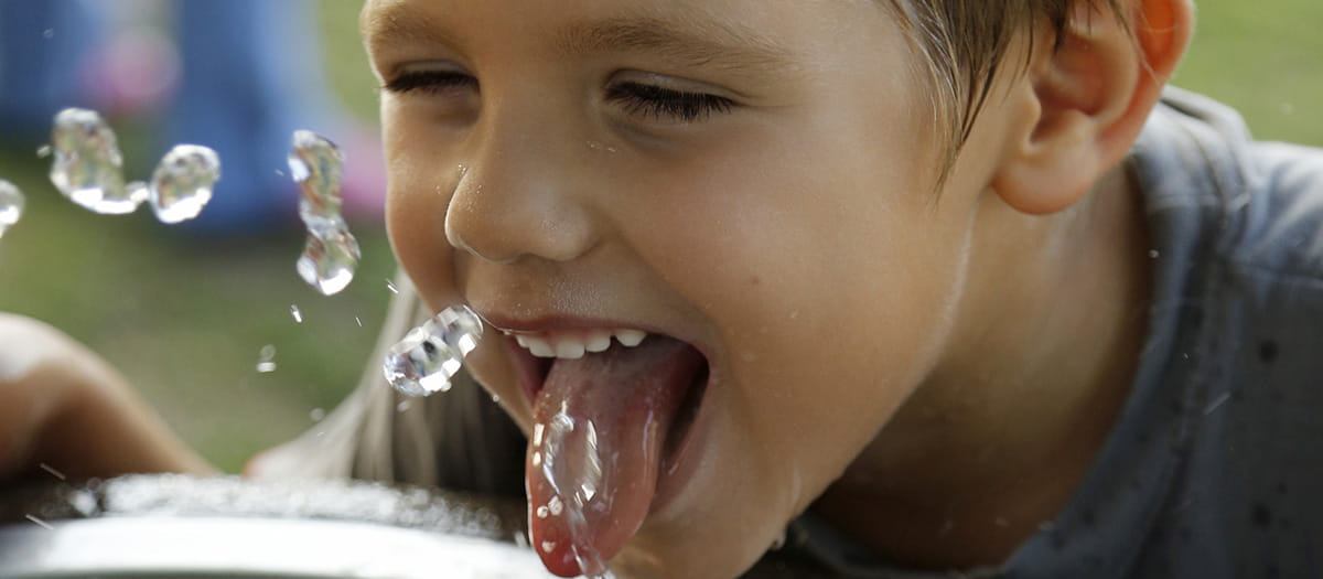 Boy drinking from a drink tap