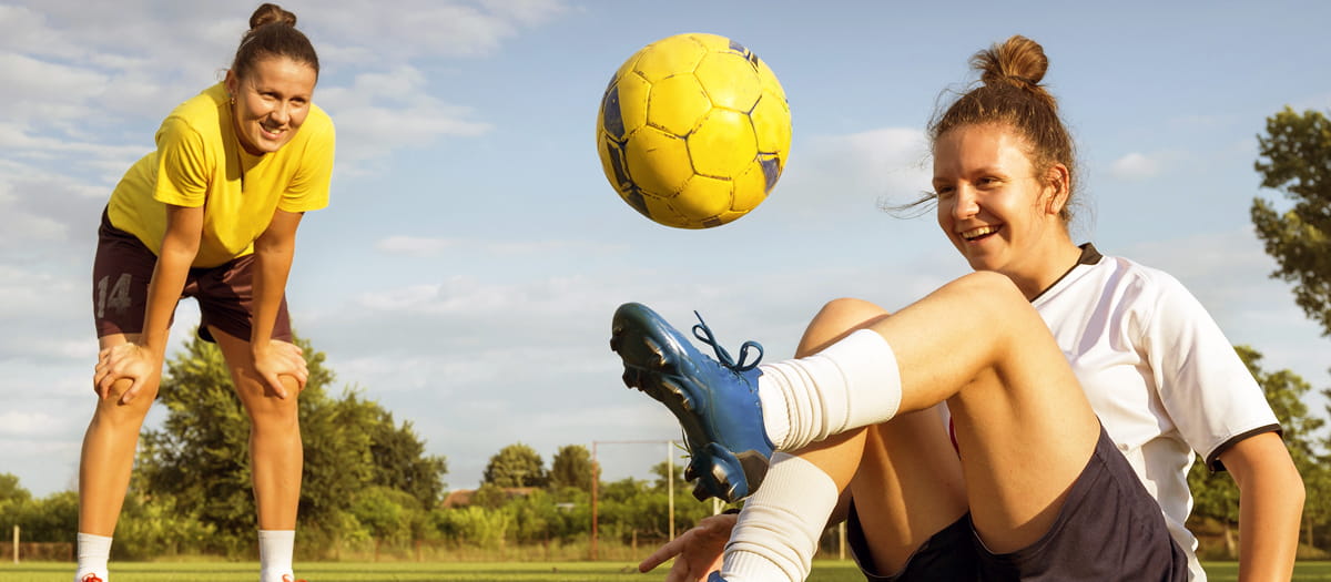 Two women kicking a soccer ball