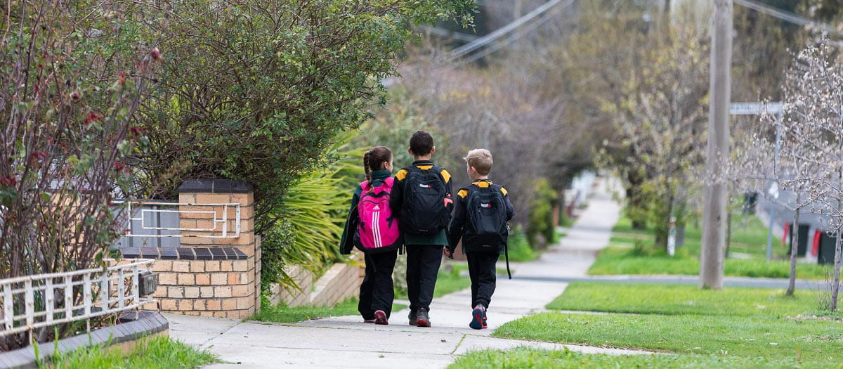 photo of three kids walking down a suburban street