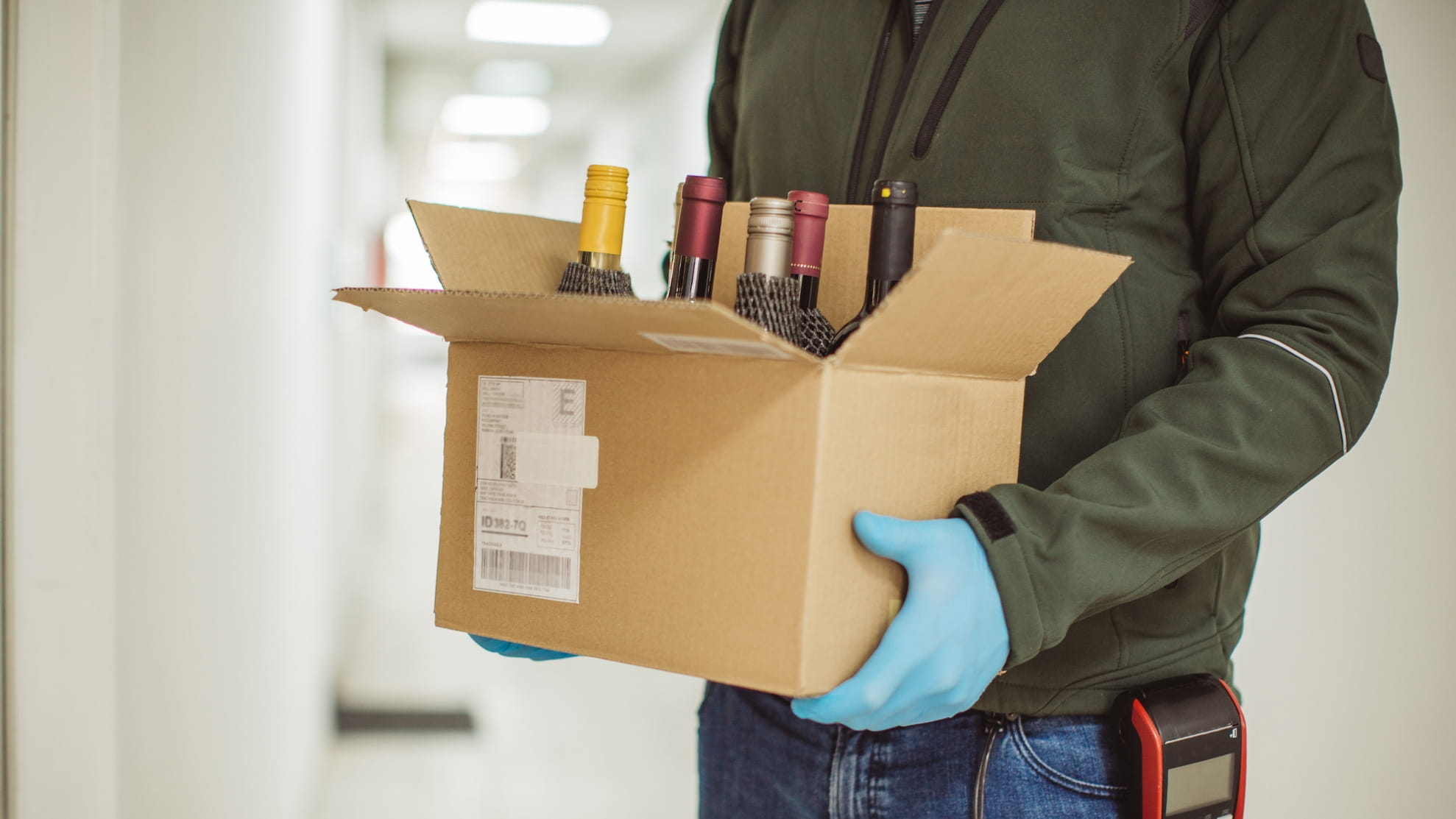 Man wearing gloves delivering box of alcohol