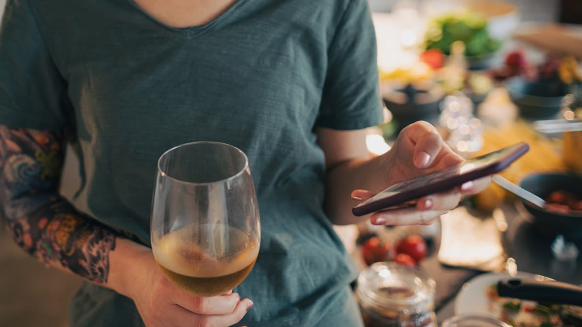 Woman holding a glass of wine and mobile phone app