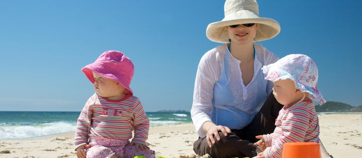 Mother and two children in hats on the beach