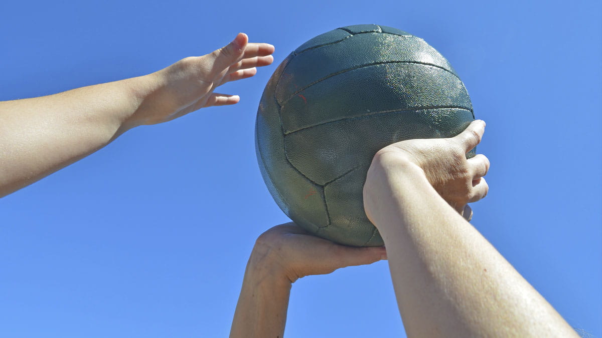 Hands holding up a netball