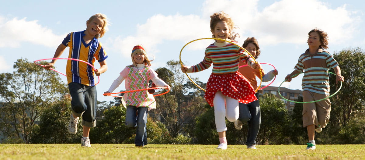 Children running with hoola hoops in an open field