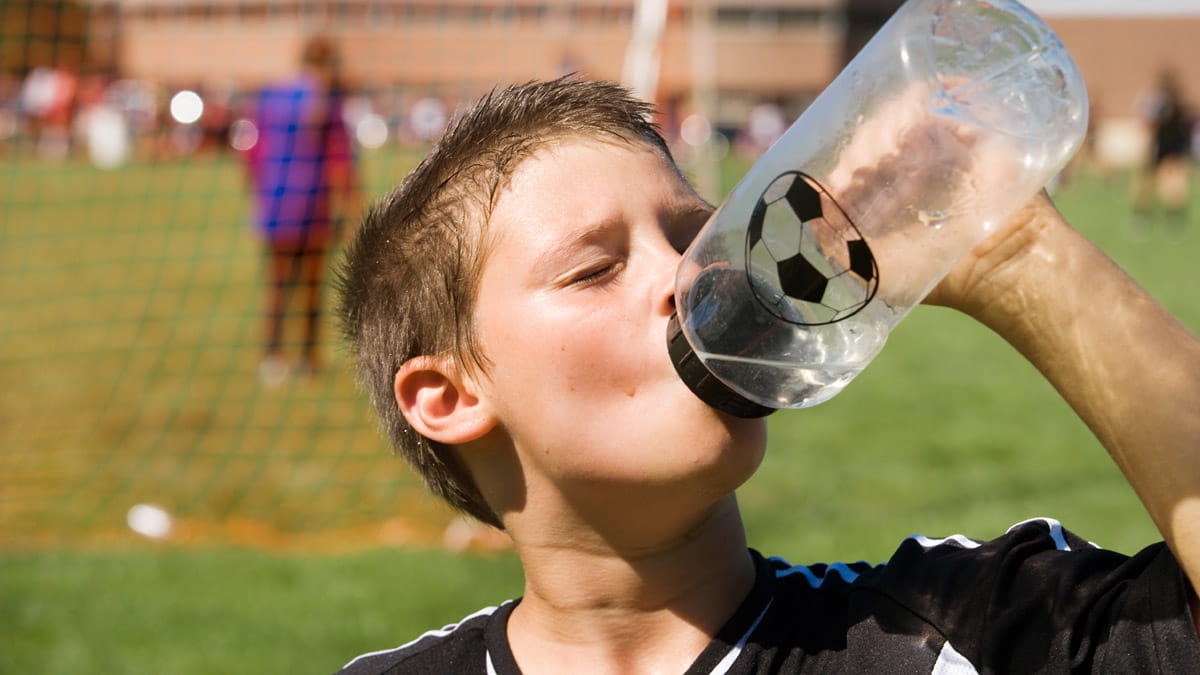 Boy drinking water on soccer field