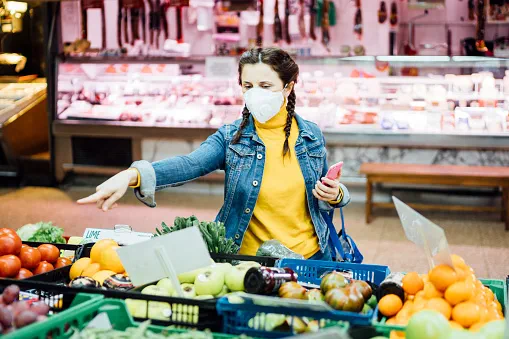 Young woman with a mask shopping at a greengrocer's