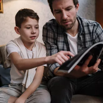 A photo of a father and son looking at a book together