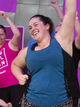 A group of women wearing active wear, smiling and dancing 