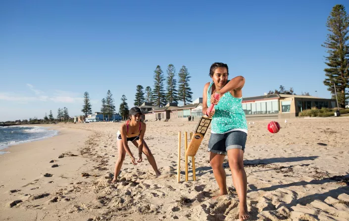 Two girls playing cricket on the beach