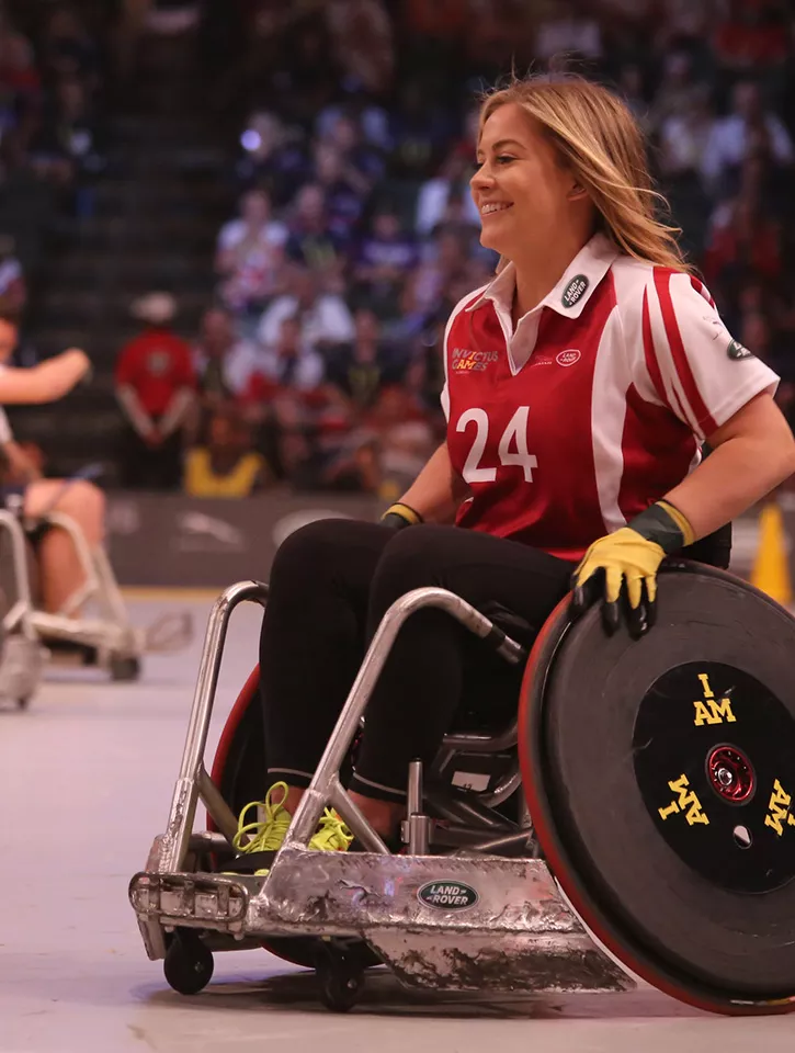 A woman in a wheelchair playing sport with a crowd behind her.