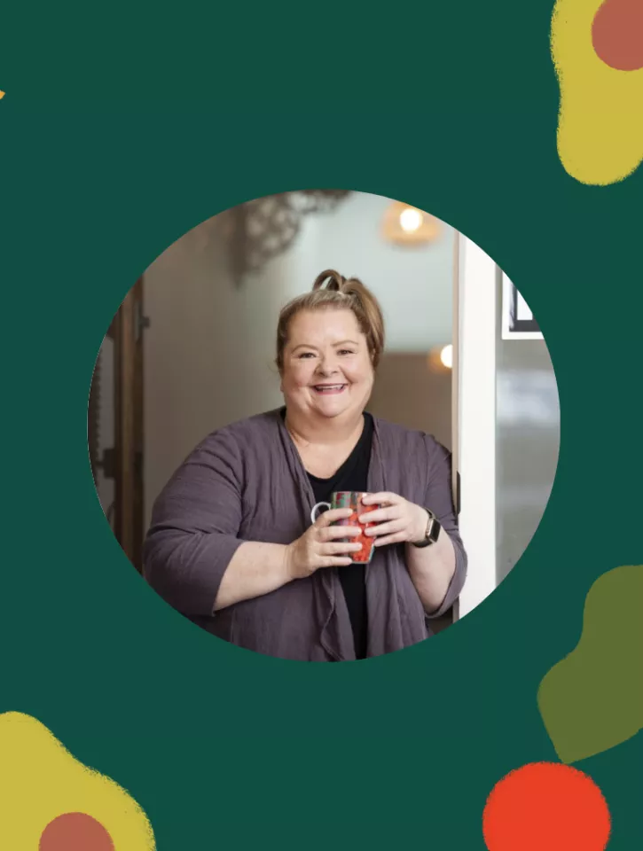 Picture of Magda Szubanski holding a mug and smiling on a green background.
