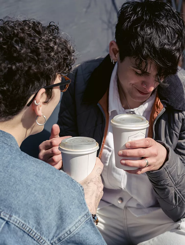 Close up shot of two people drinking coffee and chatting. 