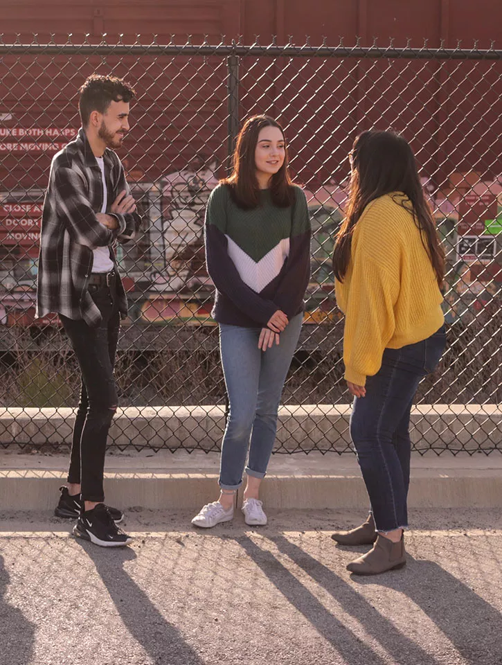 Three young people chatting in an urban environment