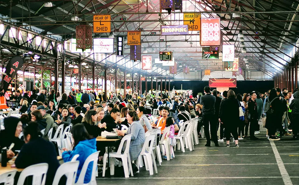 People sitting, standing and eating at the Vic Markets.
